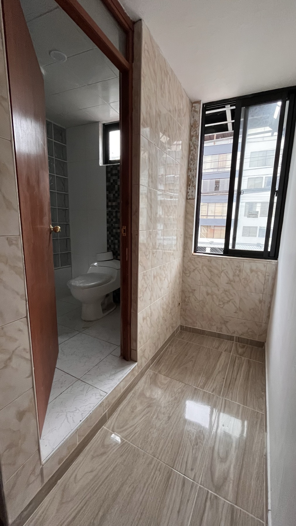 Baño propio con mayólica y área de servicio con ventana