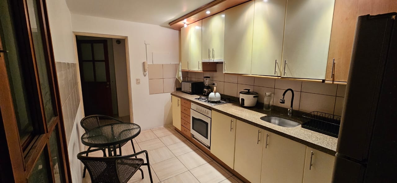 Cocina equipada con horno, refrigeradora, microondas y mesa de diario
