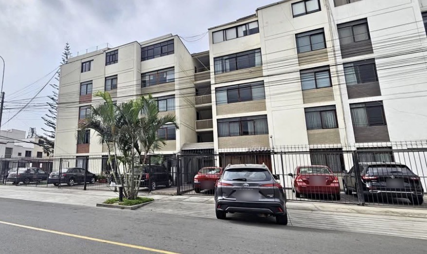 Fachada del edificio con estacionamiento enrejado al frente